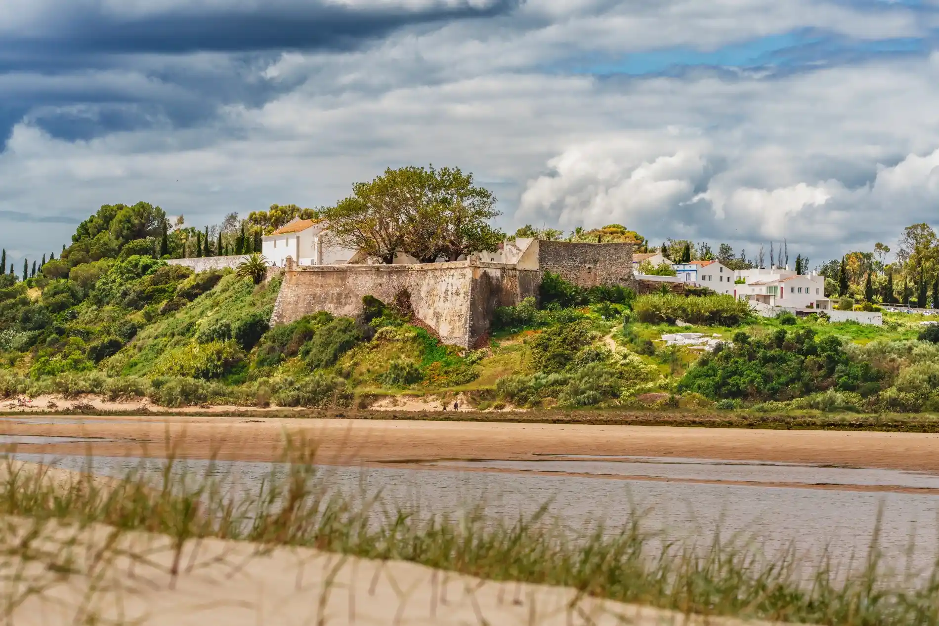 Forte de Cacela Velha sob céu dramático, junto à Ria Formosa